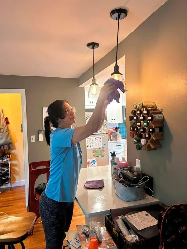 Bedigan cleaner dusting pendant lights over a counter