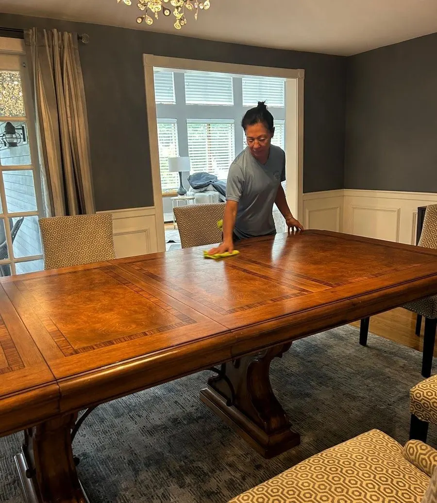 Bedigan cleaner polishing a dining table under a chandelier
