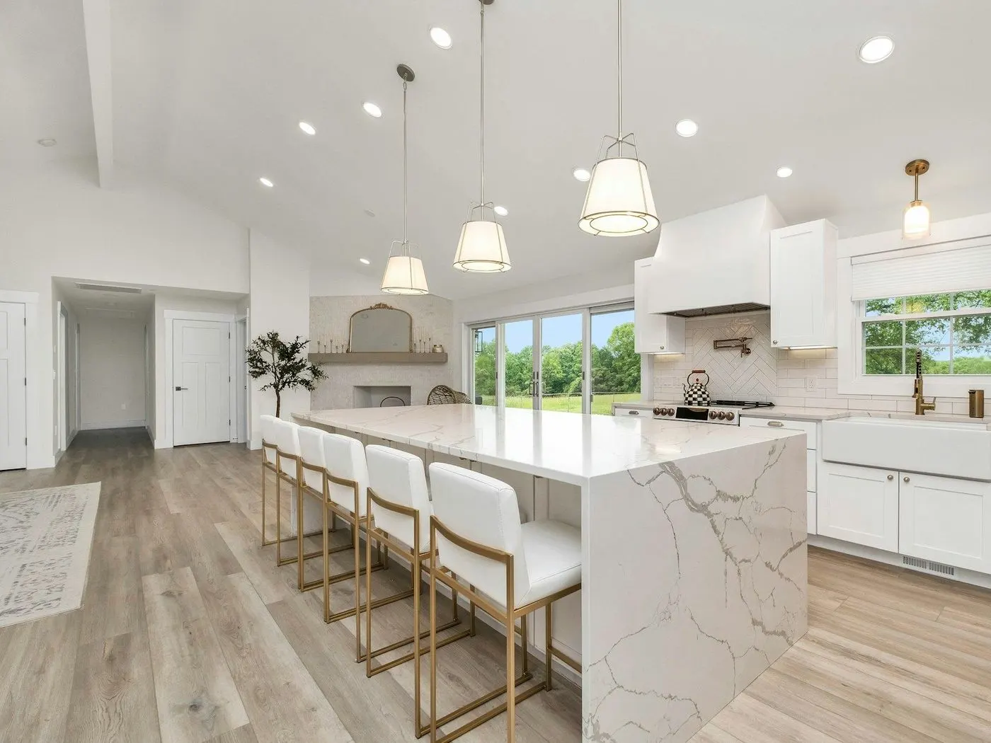 Clean white kitchen with a long marble island and pendant lights