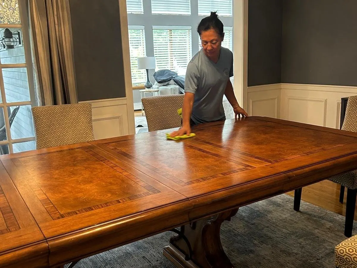 Bedigan cleaner polishing a wood dining table in a client home