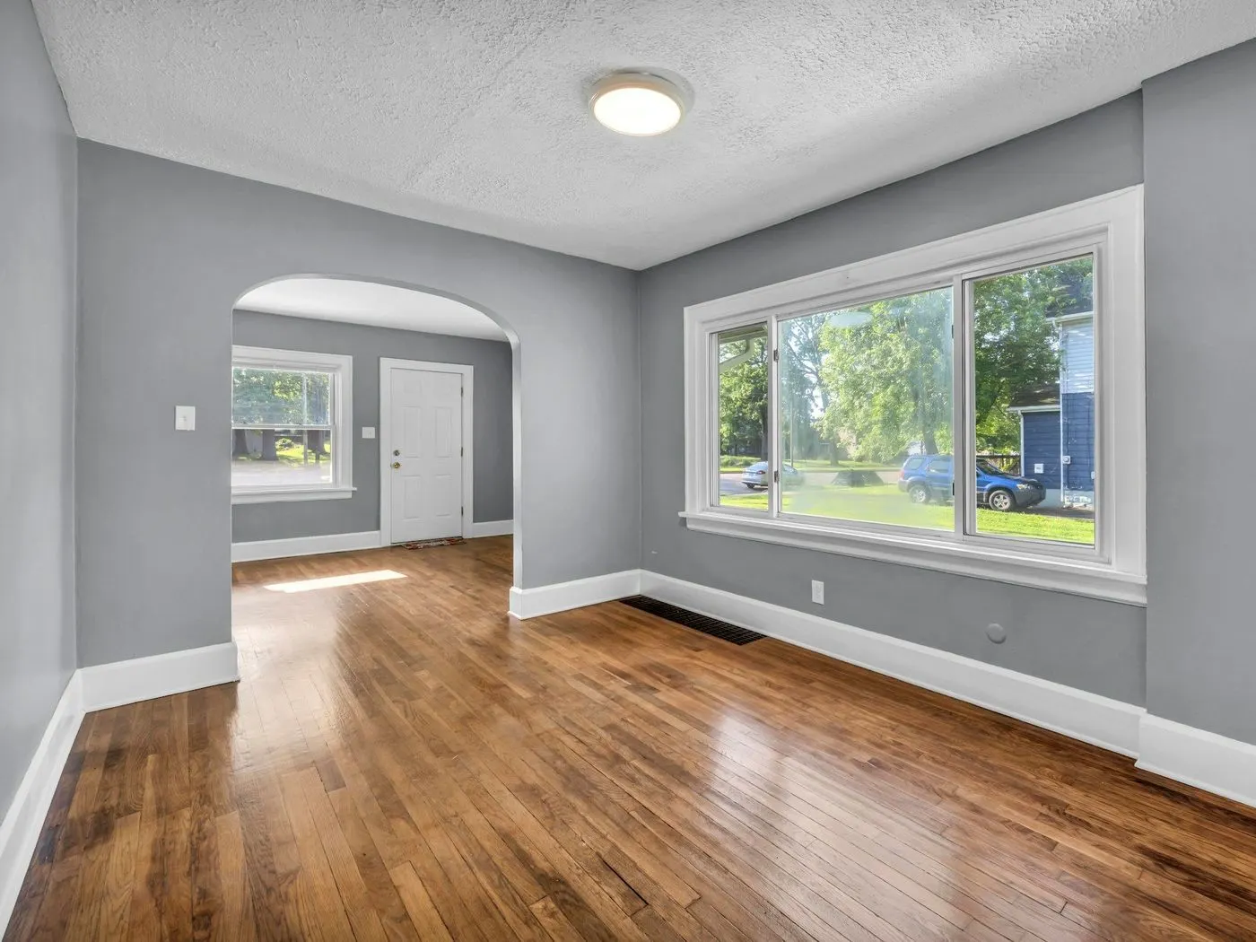 Empty living room with gray walls and wood floors after a move-out cleaning